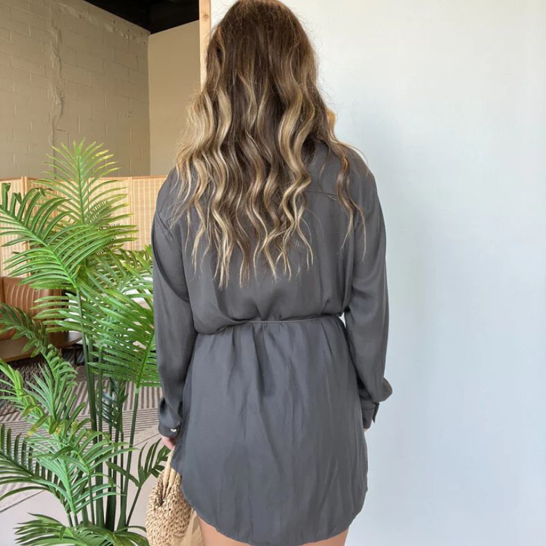 Achteraanzicht van een vrouw in de Levana™ – Satijnen Blousejurk van Inicala.nl, met golvend haar en een losvallende fit; elegant en comfortabel design voor een stijlvolle everyday look.