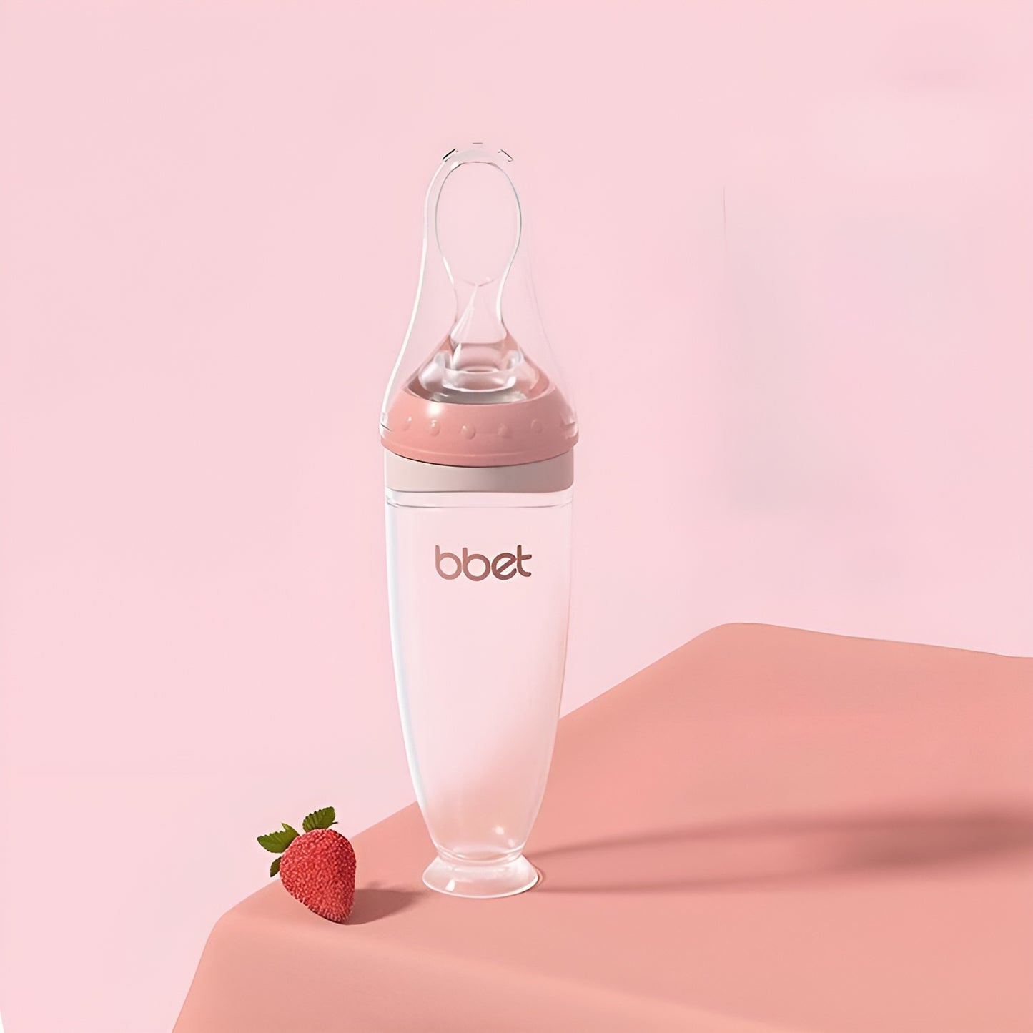 BabyHap™ Lepel-Knijpfles met roze en witte accenten op een roze ondergrond. De fles is ideaal voor stressvrij voeden, gemaakt van voedselveilige siliconen en eenvoudig schoon te maken.