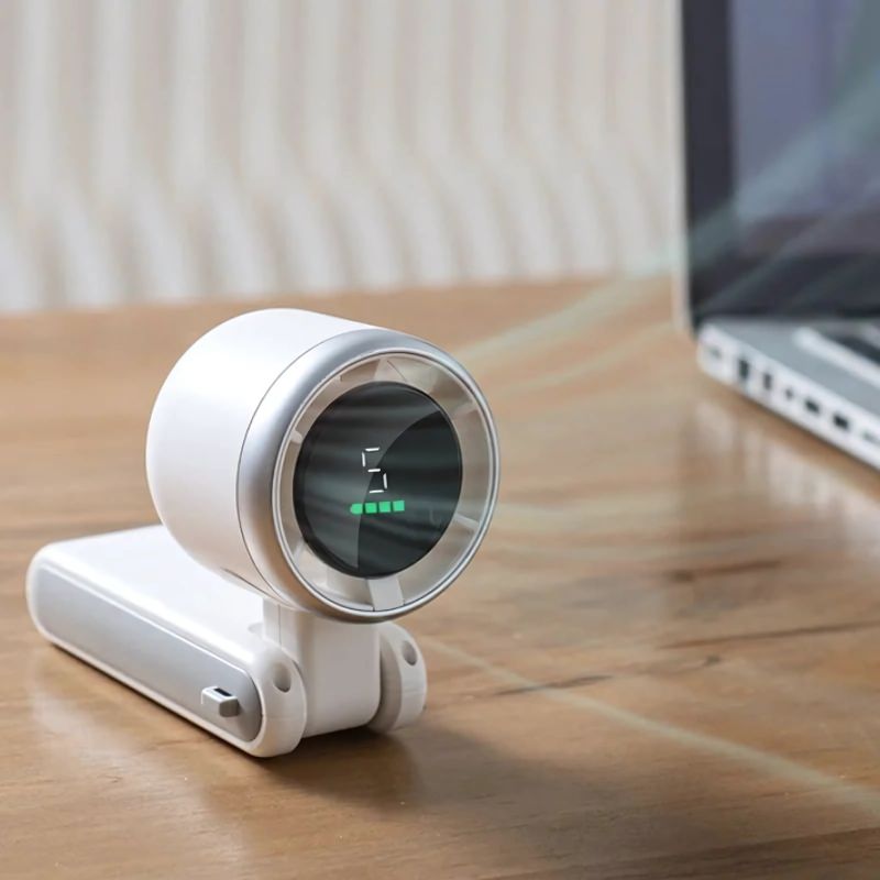 BreezeBuddy™ – Draagbare witte mini-ventilator op een houten bureau, blaast naast een open laptop. Te koop op Inicala.nl.