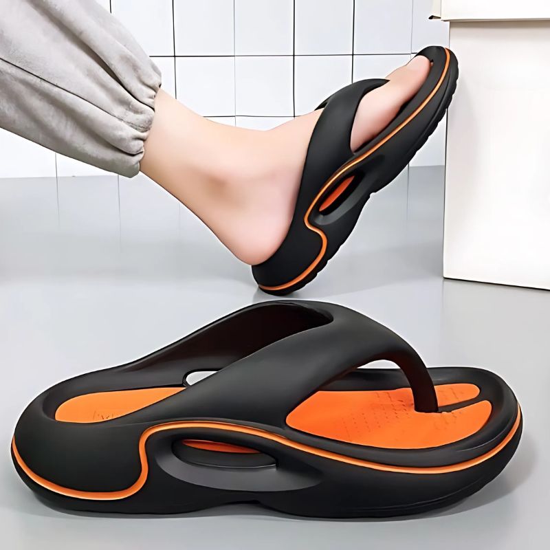 CloudRift™ – Ergonomische Slippers van Inicala.nl in zwart met oranje zool. Een stevige en comfortabele slipper die je voeten ondersteunt en demping biedt bij elke stap. Ideaal voor langdurig draagcomfort, thuis of buiten.