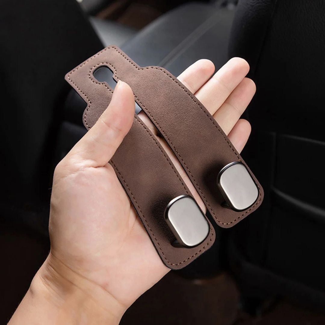 HangEase™ Organizer van Inicala.nl – luxe dubbele autostoelhaak in suède, bruin. Getoond in handpalm voor formaatvergelijking. Ideaal om tassen of accessoires s