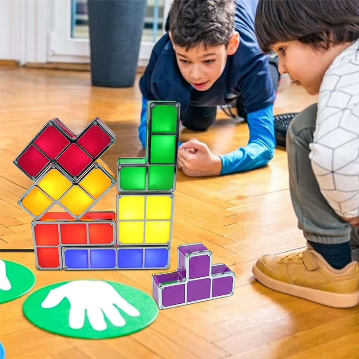 Kinderen spelen op de vloer met TetraGlow™-lichtblokken, stapelend in kleurrijke patronen. De fel verlichte blokken in rood, groen, geel, paars en blauw stimuleren creativiteit en spelplezier, terwijl ze een nostalgische sfeer oproepen. inicala