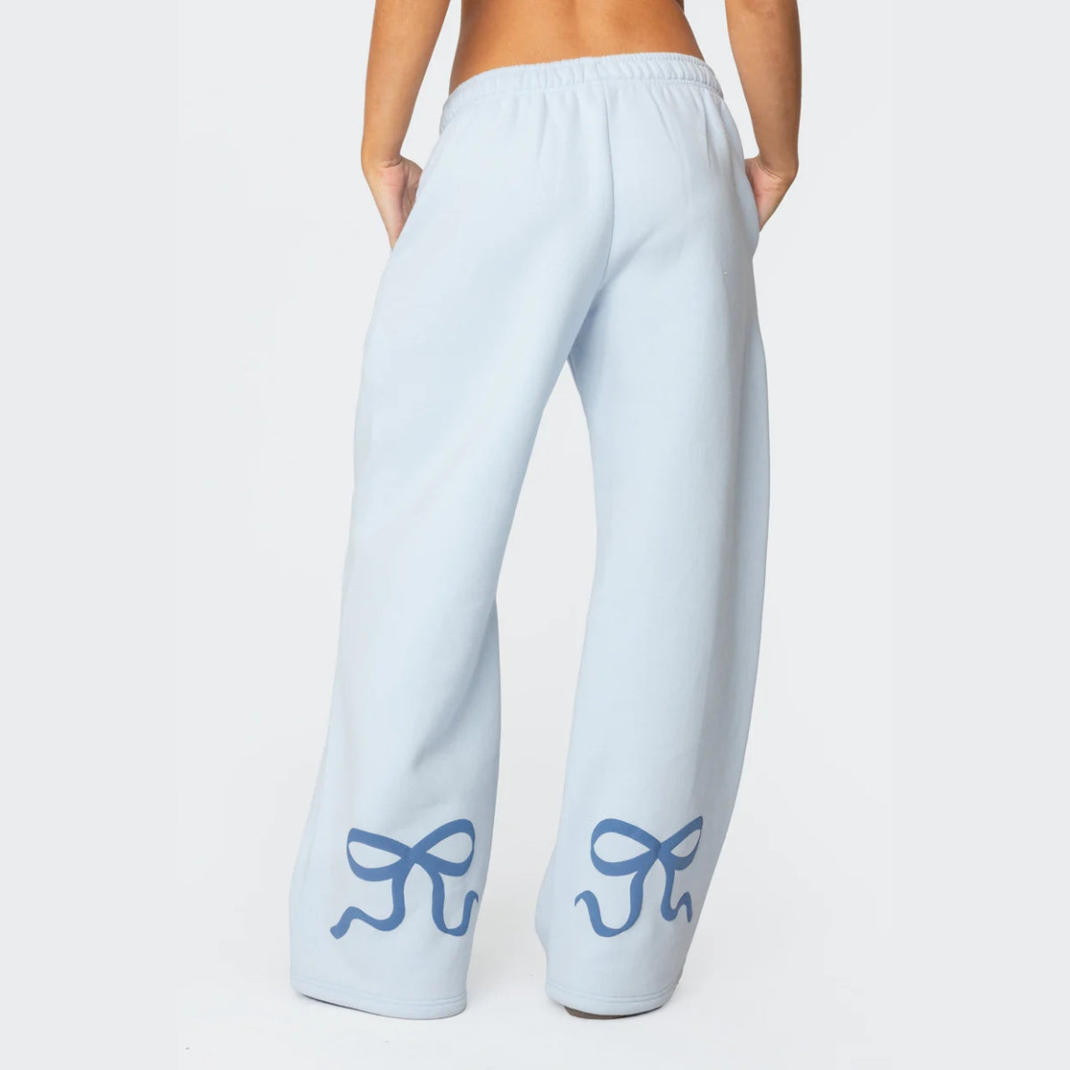 Luna Ribbon Tracksuit - Elegantie in Comfort Achterzijde van een lichtblauwe broek met speelse donkerblauwe strikdetails op de wijde pijpen. Casual en chic in één. Beschikbaar op Inicala.nl voor ultiem comfort en stijl!