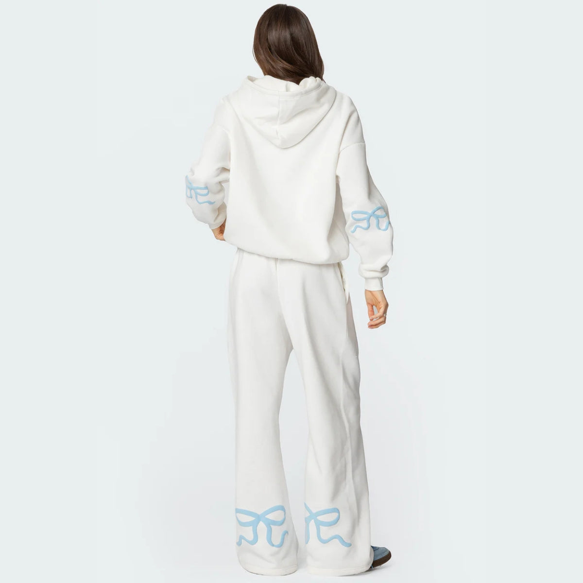 Luna Ribbon Tracksuit - Elegantie in Comfort Witte hoodie en broekset met blauwe strikaccenten. Relaxte pasvorm voor stijl en comfort. Verkrijgbaar via Inicala.nl.