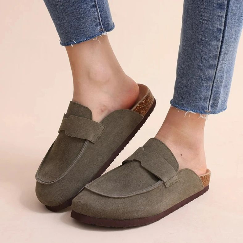 Model draagt de Nuvano™ – Suède Loafer-Clogs met Orthopedisch Comfort van Inicala.nl; stijlvolle, instapvriendelijke loafers met zachte suède afwerking en ergonomische kurkzool voor dagelijks l