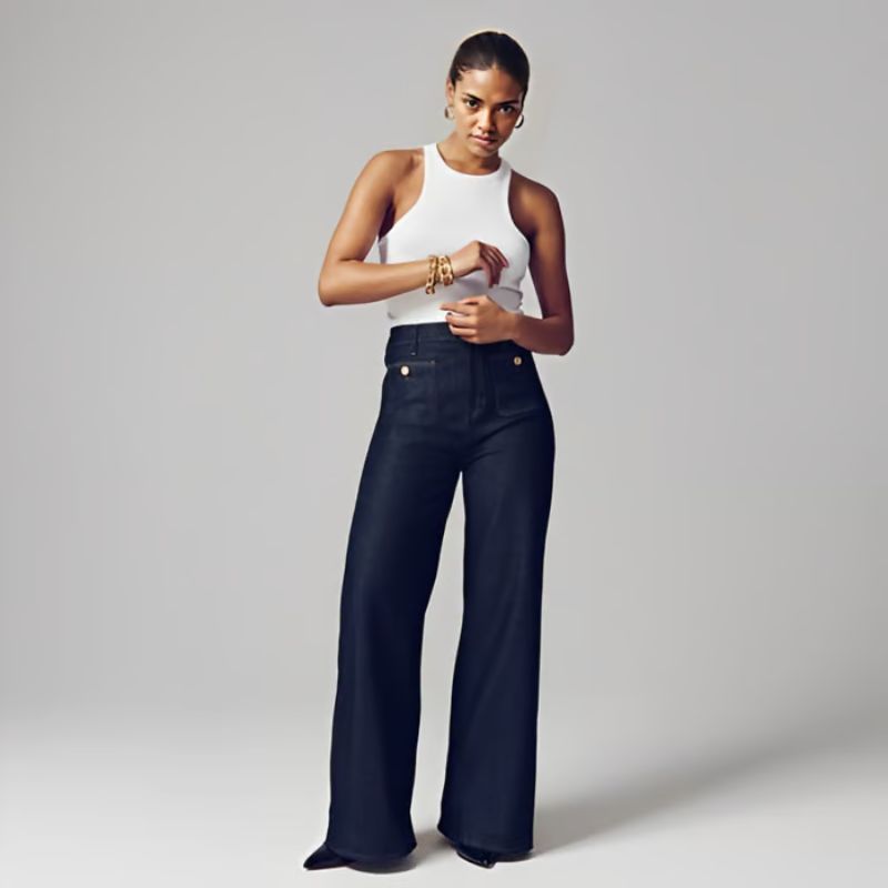 Model draagt de Riviera Flare™ jeans in donker denim van Inicala.nl – een flatterende high-waist broek met wijde pijpen, ideaal voor een krachtige, stijlvolle en comfortabele look.