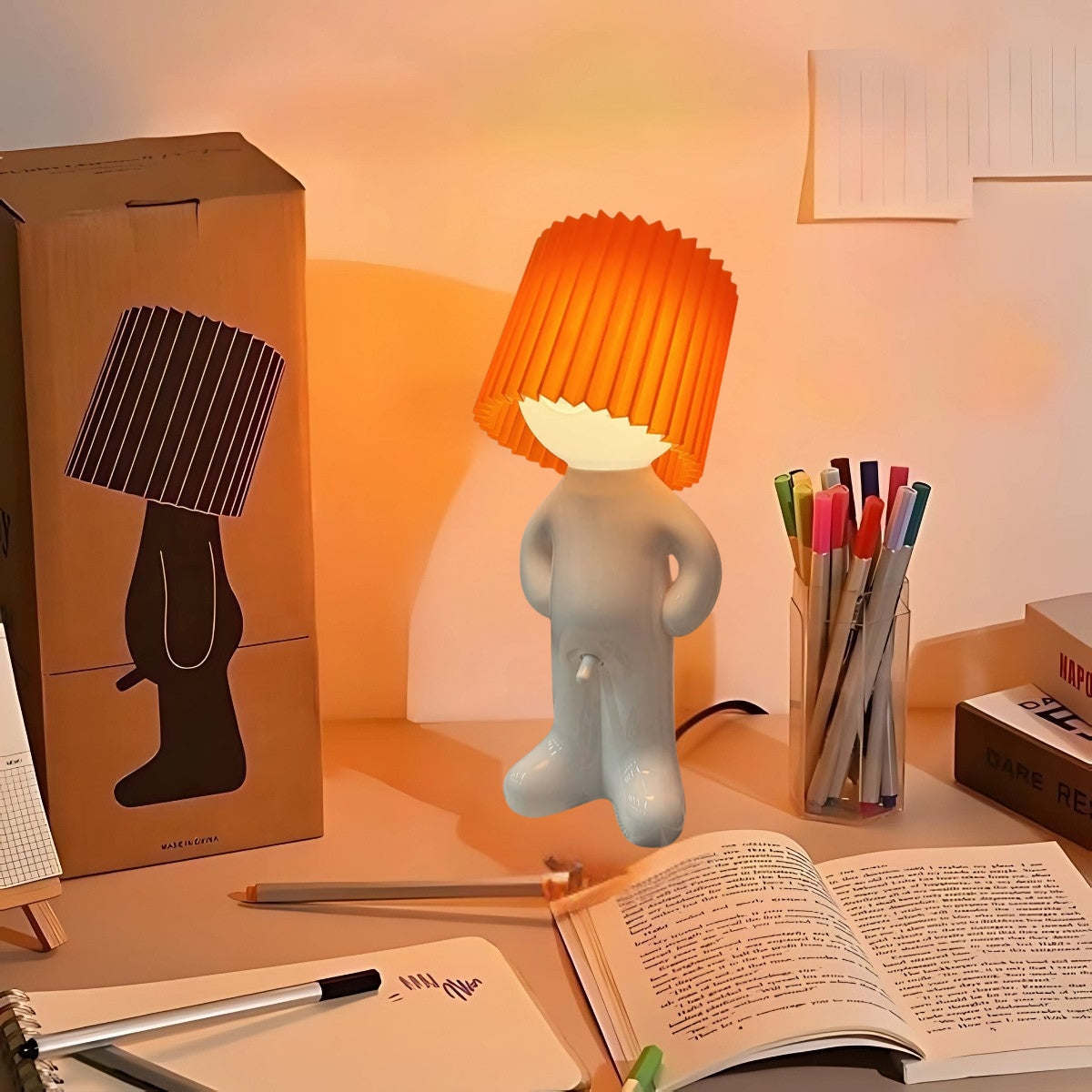 Naughty Glow Guy™ Grappig, brutaal, met een grenzeloze glimlach! Deze speelse lamp met een oranje kap voegt humor en gezelligheid toe aan elke ruimte. Perfect voor je bureau of nachtkastje. Ontdek meer op Inicala.nl!