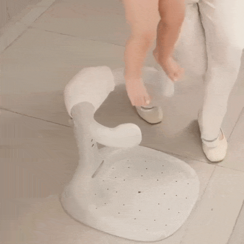 Ouder plaatst baby veilig in de Lumboo™ – Veilig Staand Badrek voor Kleintjes van Inicala.nl; het ergonomische ontwerp met zachte armsteunen biedt stabiliteit tijdens het douchen of omkleden.