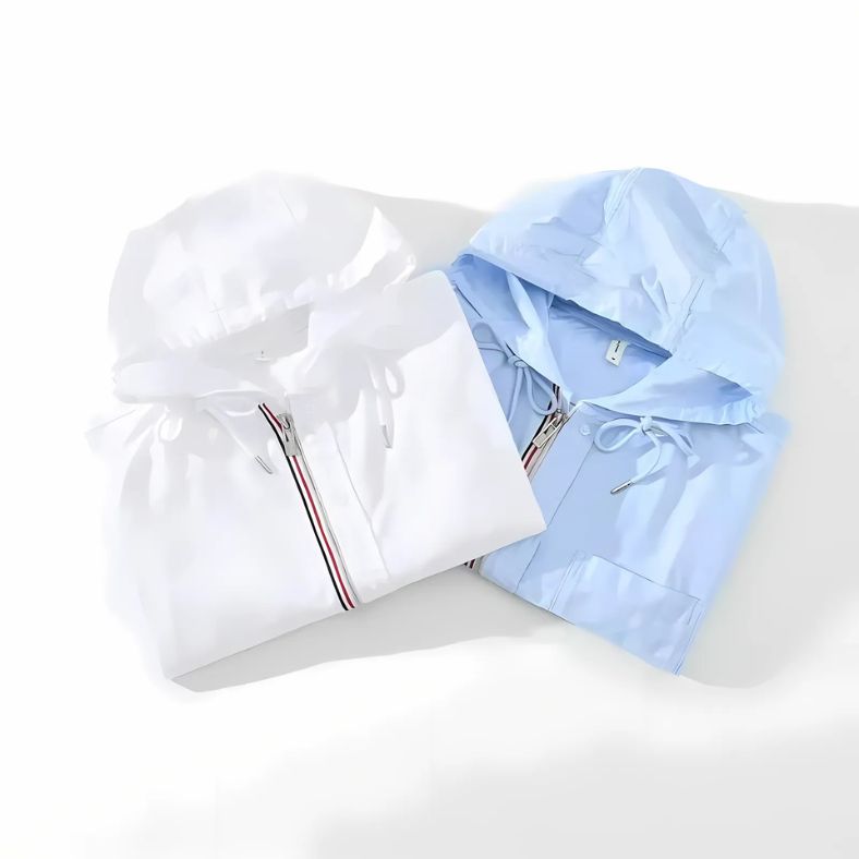 Twee opgevouwen NOMORI™ linnen hoodies van Inicala.nl in wit en lichtblauw, met capuchon, ritssluiting en trekkoord – lichtgewicht en stijlvol voor moderne, minimalistische outfits.