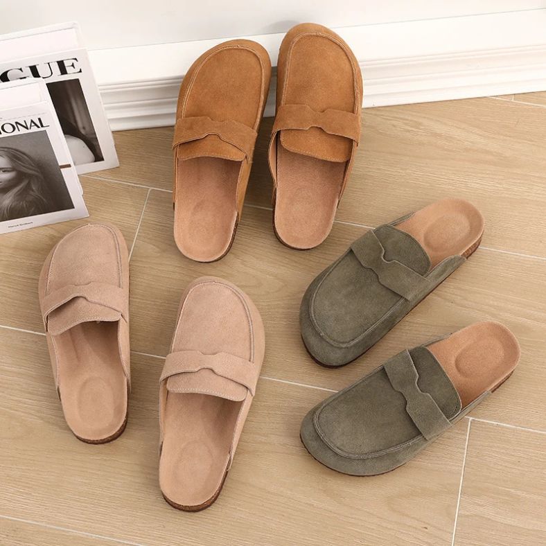 Verschillende kleuren van de Nuvano™ – Suède Loafer-Clogs met Orthopedisch Comfort van Inicala.nl op houten vloer – stijlvol, luchtig en perfect voor dagelijks comfort.