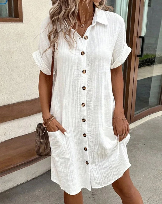 AerisBelle™ Zomerjurk in wit – luchtige jurk met knoopsluiting, korte mouwen en grote zakken. Perfect voor warme dagen, nu verkrijgbaar op Inicala.nl.