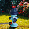 De SplashBall™ brandkraan-watersproeier in een zonnige achtertuin met kleurrijke bloemen, aangesloten op een tuinslang voor verfrissende waterpret bij elke slag. Beschikbaar op Inicala.nl.
