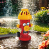 De vrolijke SplashBall™ brandkraan-watersproeier in een bloeiende tuin, spuit verfrissend water voor uren buitenspeelplezier. Eenvoudig aan te sluiten op je tuinslang, te koop op Inicala.nl.