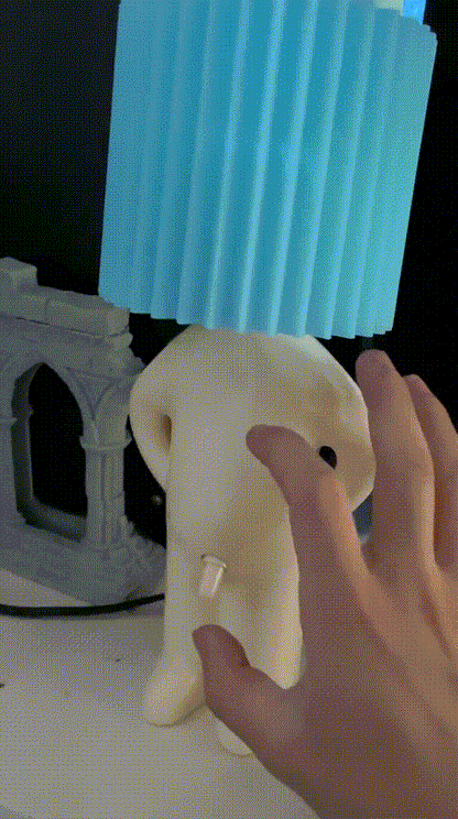 Een hand schakelt de Naughty Glow Guy™ in door de ondeugende schakelaar te gebruiken, terwijl de blauwe lampenkap een warme gloed verspreidt. Voeg humor en stijl toe aan je ruimte! Meer info op Inicala.nl.