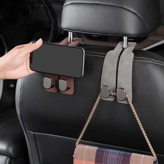 HangEase™ Organizer van Inicala.nl – luxe dubbele autostoelhaak in bruin en grijs suède, bevestigd aan een hoofdsteun. Te zien als tassenhaak én handige houder voor een telefoon, ideaal voor een opgeruimde en slimme auto-i