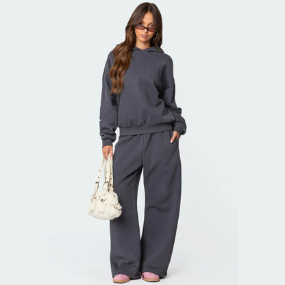 Luna Ribbon Tracksuit - Elegantie in Comfort Een donkergrijs, loszittend trainingspak met delicate roze strikdetails, perfect voor een casual en stijlvolle look. Ontdek exclusief op Inicala.nl en omarm moeiteloos comfort e