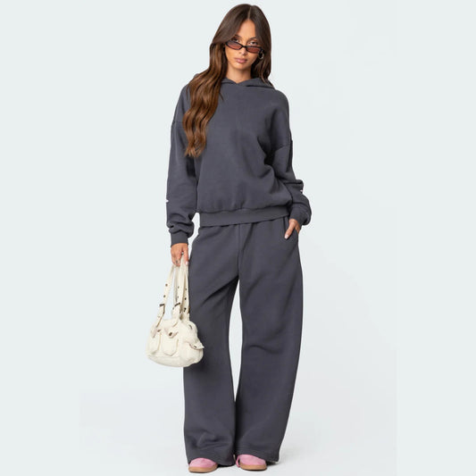 Luna Ribbon Tracksuit - Elegantie in Comfort Een donkergrijs, loszittend trainingspak met delicate roze strikdetails, perfect voor een casual en stijlvolle look. Ontdek exclusief op Inicala.nl en omarm moeiteloos comfort e
