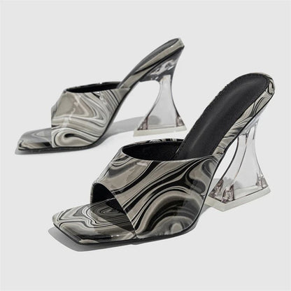 Marbellé™ – Waar Kunst en Mode Samenkomen van Inicala.nl. Zwart-witte hakslippers met transparante hak, marmerlook en comfortabele pasvorm. Tijdloos en stijlvol design.