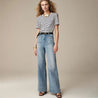 Model draagt de Riviera Flare™ jeans in lichtblauw van Inicala.nl – een flatterende high-waist flare jeans met gouden knopen en rechte pijpen, ideaal voor een tijdloze en comfortabele everyday look.