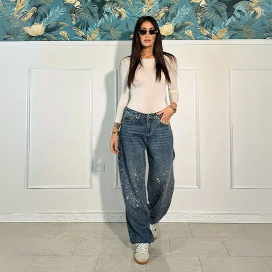 Model draagt de Stardust Cargo™ – Shiny Denim Statement van Inicala.nl, een losse denim broek met glinsterende strassdetails en cargozakken, perfect voor een opvallende en zelfverzekerde look.