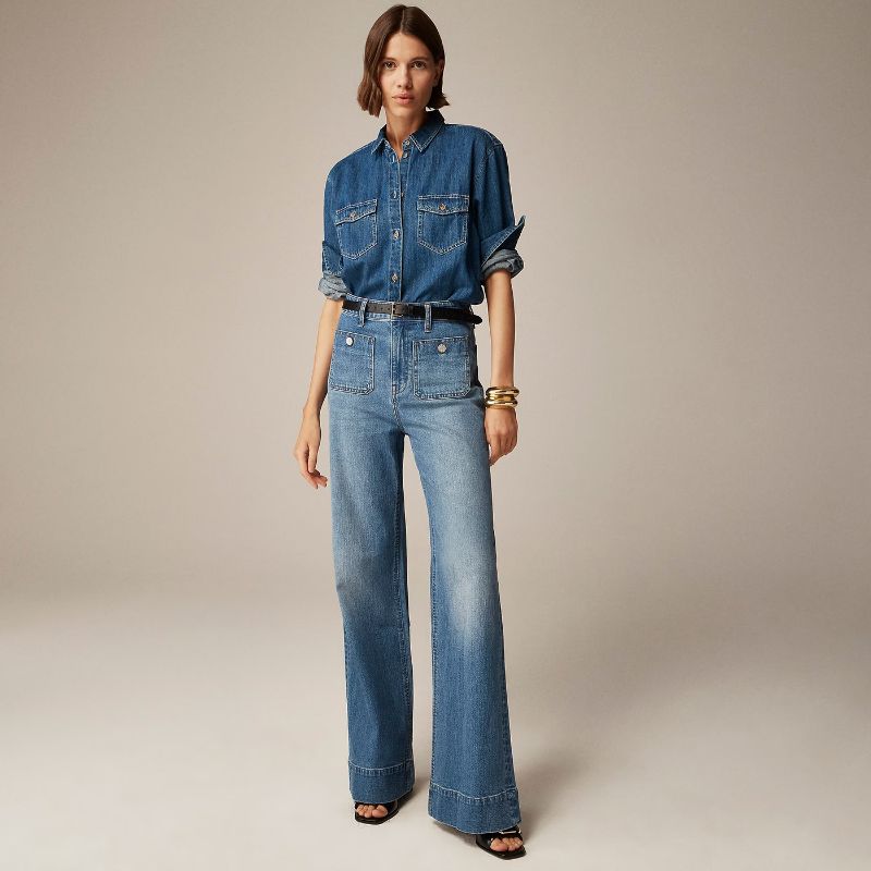 Model showt de Riviera Flare™ jeans in middenblauw van Inicala.nl – high-rise denim met flatterende wijde pijpen en opvallende knoopdetails, perfect voor een tijdloze en stijlvolle everyday look.