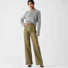 Model toont de Riviera Flare™ jeans in olijfgroen van Inicala.nl – high-waist broek met flatterende flare fit en gouden knopen, perfect voor een stijlvolle look met comfort en karakter.