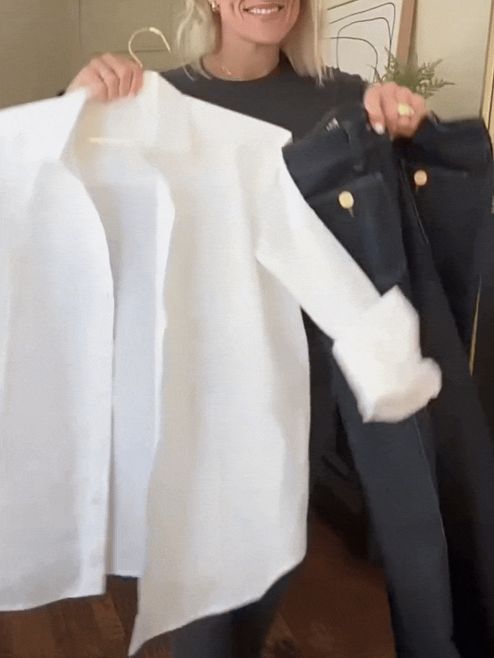 Vrouw toont een witte blouse en de Riviera Flare™ jeans van Inicala.nl met gouden knoopdetails – een tijdloze combinatie voor een stijlvolle, moeiteloze look met Franse flair.