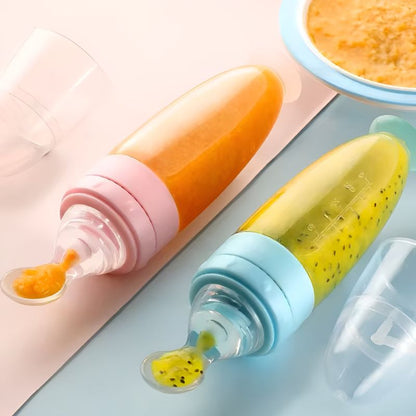 twee BabyHap™ Lepel-Knijpflessen gevuld met feloranje en groene puree. De flessen hebben zachte lepeltuiten en gekleurde doppen in roze en blauw. Een transparante beschermkap ligt ernaast.